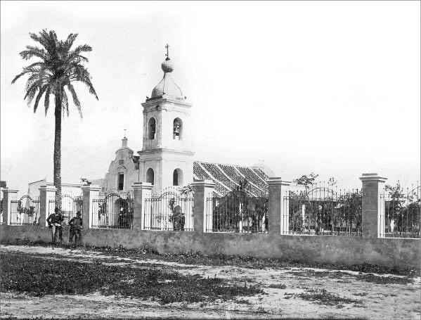 Imagen de la vieja
capilla de Guadalupe, erigida por el ermita&ntilde;o Francisco Javier de la Rosa en 1780.
La actual Bas&iacute;lica comenz&oacute; a construirse en 1904 bajo las &oacute;rdenes del arquitecto
Juan Bautista Arnaldi y fue inaugurada el 8 de mayo
de 1910. Qued&oacute; como testigo de la antigua capillita la palmera, plantada el 5
de febrero de 1820 en ocasi&oacute;n de la boda de Do&ntilde;a Mar&iacute;a del Barco y que fuera troncada
por una tormenta en las &uacute;ltimas d&eacute;cadas del S. XX. (Fototeca del Archivo General de la Provincia.)